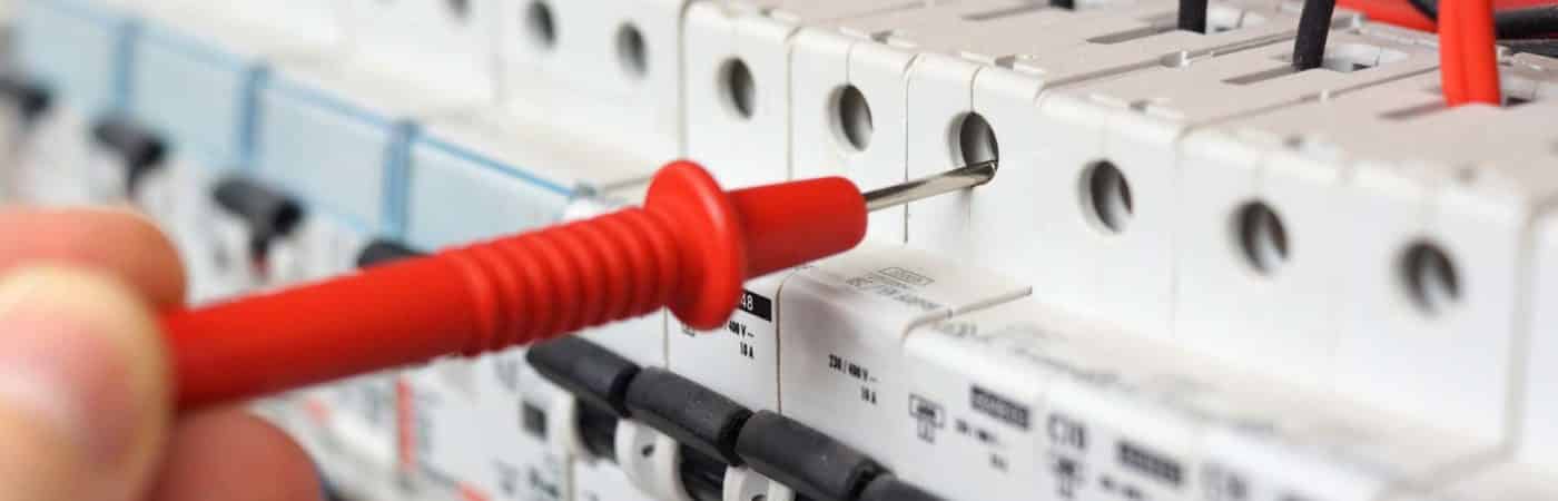 Hand of an electrician with multimeter probe at an electrical sw Hand of an electrician with multimeter probe at an electrical switchgear cabinet - Big Easy Electricians