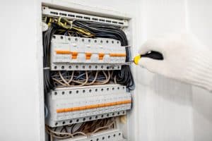 Electrician installing or repairing apartment electrical panel, close-up view